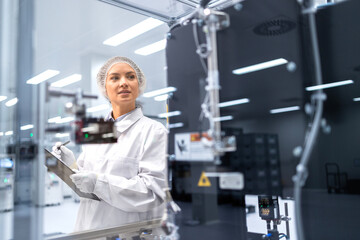 Female factory engineer inspecting process of automated robotic production.