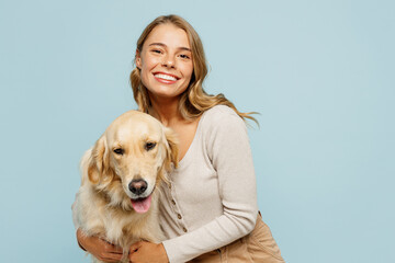 Young satisfied happy owner woman with her best friend retriever she wear casual clothes cuddle hug dog look camera isolated on plain pastel light blue background studio. Take care about pet concept.