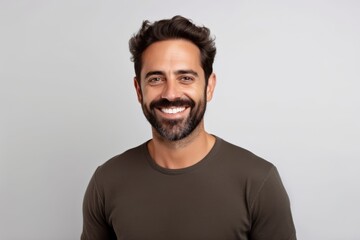 Portrait of a happy young man smiling and looking at camera against grey background