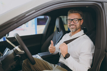 Adult happy fun man customer male buyer client wear shirt drive electric car with seat belt choose...