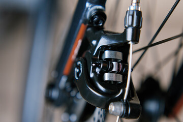 Part of the bicycle's braking system. Grey metal brake disc and brake pads on road bike, close up.