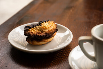 Sweet pastry with chocolate topping with an espresso on a wooden table, Sicily