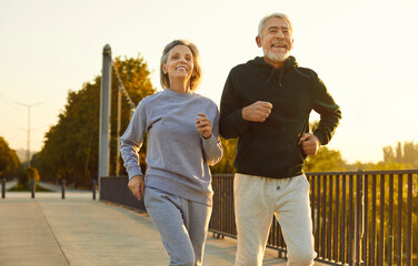 Happy smiling senior people wearing sportswear jogging outdoors having sport workout. Elderly...