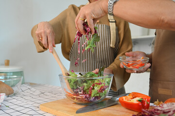 Retirement senior couple making organic fresh salad together in kitchen. Healthy eating concept