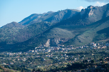 Panoramic view over the rough mountains with houses and blue sky around Cannizaro- Favare, Italy