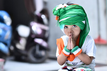Innocent Indian baby girl wearing Indian national flag color white t-shirt, tricolor turban and...