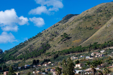 Panoramic view over the rough mountains with houses and blue sky around Cannizaro- Favare, Italy