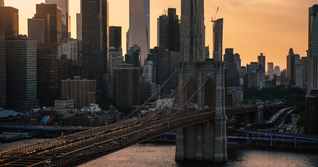 Aerial Cinematic Drone Scene Near the Brooklyn Bridge with Lower Manhattan Skyscrapers Cityscape. Beautiful Evening Sun Shining with Warm Sunset Light. Photo of a Suspension Bridge Architecture