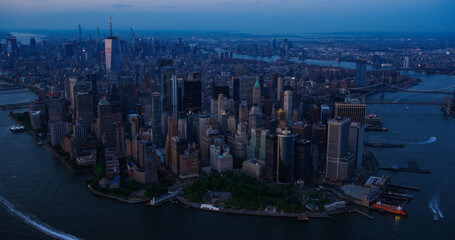 Fototapeta na wymiar Evening Aerial View of Lower Manhattan Architecture. Panoramic Shot of Wall Street Financial District from a Helicopter. Office Buildings Next to Water Transportation in Hudson and East Rivers