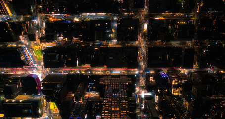 Top Down Aerial View of New York City Streets Lit with Neon Lights from Billboards. Busy Metropolis Traffic with Cars, Yellow Taxis, Commercial Vehicles and People Walking