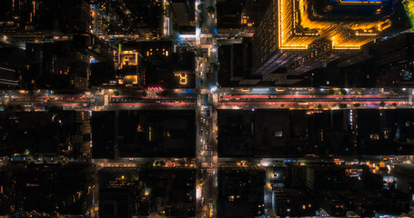 Top Down Aerial View of New York City Streets at Night with Visible Grid System, Business and Residential Building Roofs. Busy Center with Traffic, Cars, Yellow Taxis, Commercial Vehicles, Pedestrians