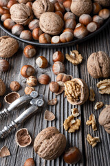 Walnuts and hazelnuts nuts open with a vintage nut cracker on old wooden table. Food photography