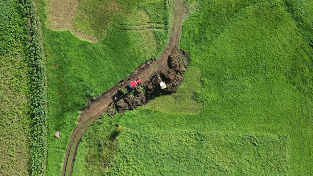Topdown On Backhoe Excavating Soil In The Meadow. Earthworks In Zas, A Coruna, Spain. aerial shot