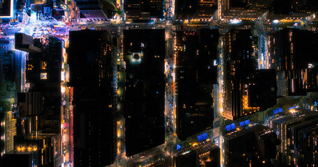 Top Down Aerial View of New York City Streets at Night with Visible Grid System, Business and Residential Building Roofs. Busy Center with Traffic, Cars, Yellow Taxis, Commercial Vehicles, Pedestrians