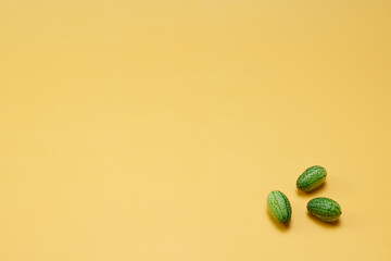 マイクロきゅうりを数粒右下に配置した黄色系背景あり俯瞰撮影