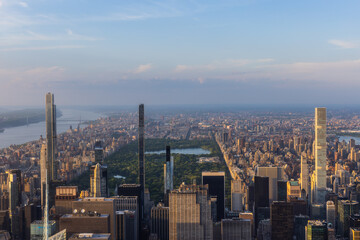 New York Cityscape at Sunset. Aerial Photo from a Helicopter. Modern Skyscraper Buildings Around Central Park in Manhattan Island. Focus on Nature, Trees and Lakes in the Park in the City