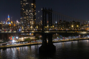 Fototapeta premium Iconic New York City Landscape Over East River with Skyscrapers, Brooklyn Bridge, Cars and Ferry Boats. Cinematic Night Urban Skyline