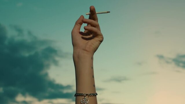 Girl with green hair smoking cigarette at sunset outdoors