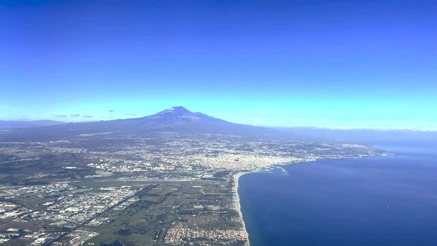 Ripresa aerea del vulcano Etna, con la citt&agrave; di Catania e il suo porto