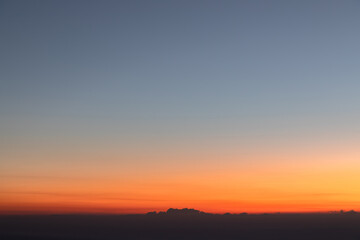 Fototapeta na wymiar Heaven at early morning with copy space. Sunset, sunrise backdrop.Predawn clear sky with orange horizon and blue atmosphere. Smooth orange blue gradient of dawn sky.