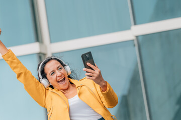 woman with headphones and mobile phone or smartphone excited with joy