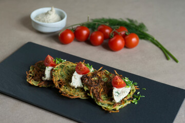 Zucchini pancakes with feta cheese, cherry tomatoes and herbs