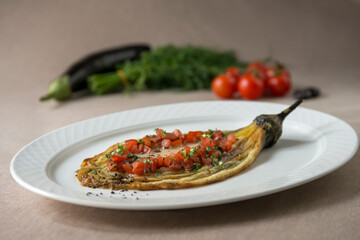 Eggplant baked with tomato and parsley on a white plate