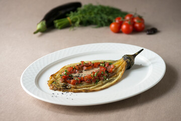 Eggplant baked with tomato and parsley on a white plate