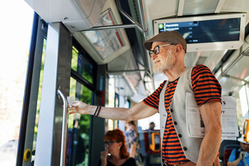 Elderly man traveling through the city by bus, standing by door. Senior city commuter taking tram to grocery, using public transportation.