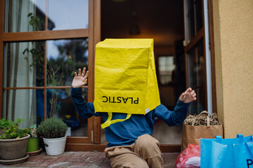 Boy put recycling bag for plastic waste on head. Boy sorting the waste according to material into...