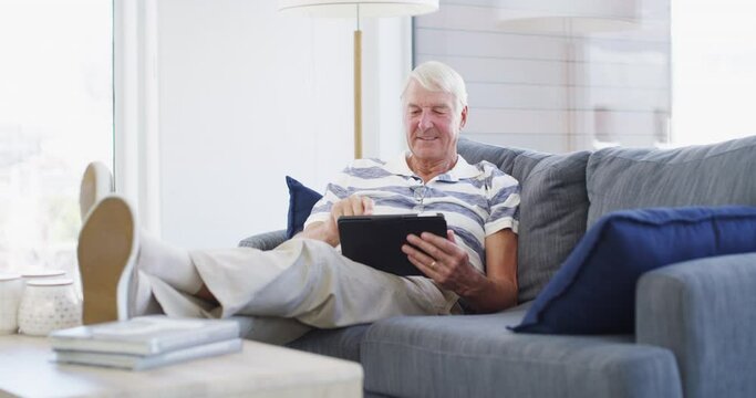 Senior man, tablet and relax on sofa for reading news app, social network post or multimedia at home. Portrait, elderly guy and laugh for digital blog, online shopping or download ebook in retirement