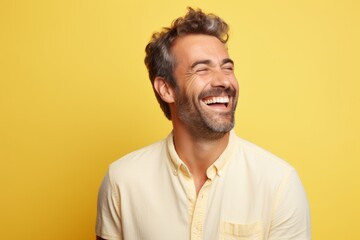 Portrait of a happy man laughing at camera over yellow background.