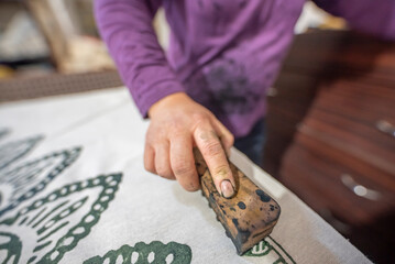Womans hand working with fabric printing mold and ink traditional writing and woodblock printing...