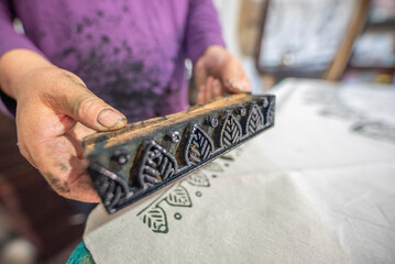 Womans hand working with fabric printing mold and ink traditional writing and woodblock printing...