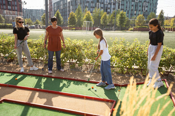 Naklejka premium White golf ball rolling down golf hole on putting green with evening golf course backdrop 