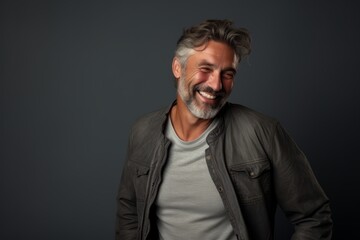 Handsome middle-aged man with grey hair and beard in casual clothes posing in studio.