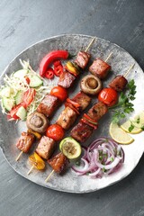 Delicious shish kebabs with vegetables on grey textured table, top view