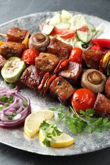 Delicious shish kebabs with vegetables on table, closeup