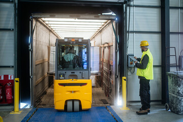 Warehouse receiver overseeing the storing of delivered items, holding tablet, looking at cargo...