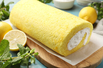Delicious cake roll, mint and lemons on table, closeup