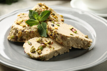 Tasty halva with pistachios and mint on table, closeup