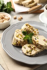 Tasty halva with pistachios and mint on table, closeup