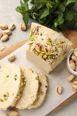 Tasty halva with pistachios and mint on light grey table, top view