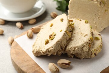 Tasty halva with pistachios on light grey table, closeup