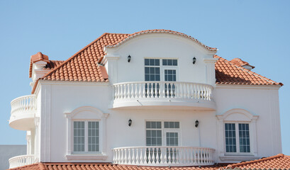 A modern classic house, luxury villa, mansion with white walls, terracotta clay, ceramic roof, large windows and semi-circle open balconies.