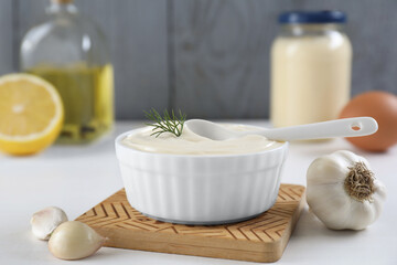 Fototapeta na wymiar Fresh mayonnaise sauce in bowl and ingredients on white table