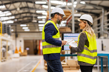 Female engineer and male project manager standing in modern industrial factory, talking about production. Team management in manufacturing facility