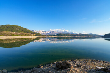 Obraz premium Reflection of trees and green leaves in the lake water. Liquidambar orientalis protected area in Burdur Turkey. Karacaoren ( barrage ) dam lake. Panorama.