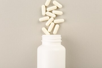 Bottle and vitamin capsules on light background, top view