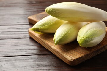 Raw ripe chicories on wooden table, closeup. Space for text